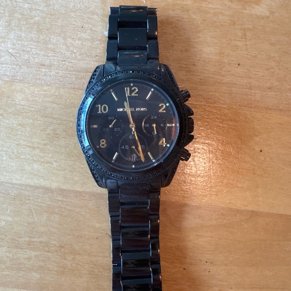 Black and woman’s Michael Kors watch